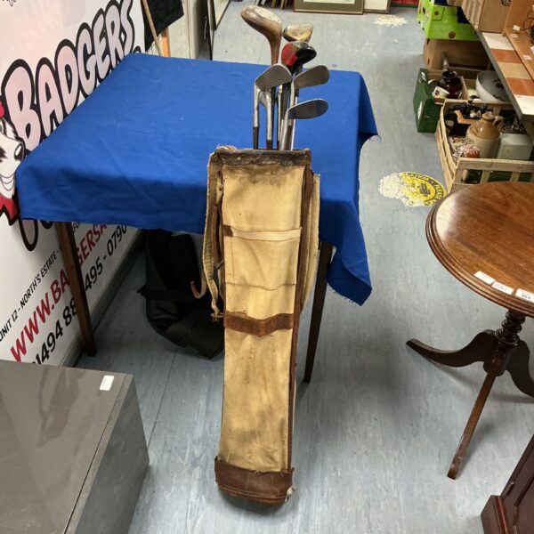 Vintage golf clubs in a worn canvas bag, antique sporting equipment.