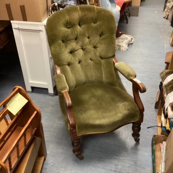 Vintage green armchair with wooden legs and caster wheels.