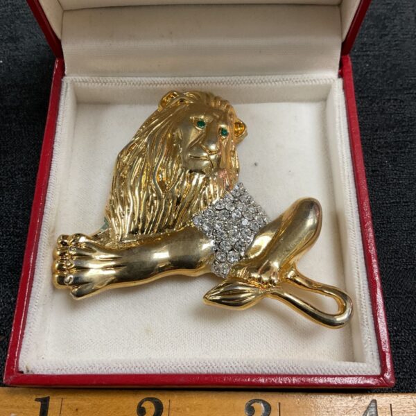 Vintage goldtone lion brooch displayed in a red box.