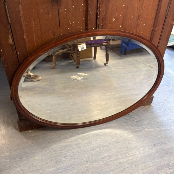 Vintage mahogany oval mirror for wall decor.