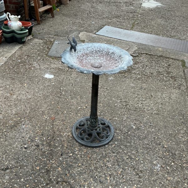 Vintage metal birdbath in a garden setting.