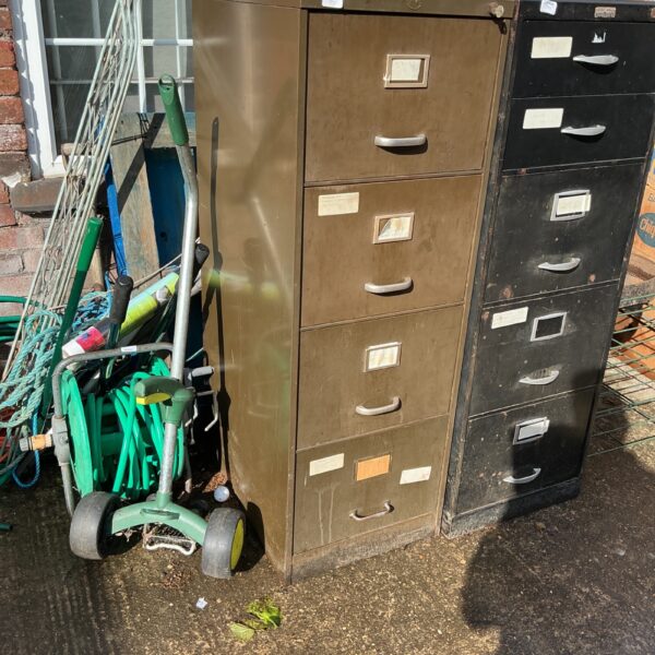 Vintage metal filing cabinet with four drawers, showing signs of wear.