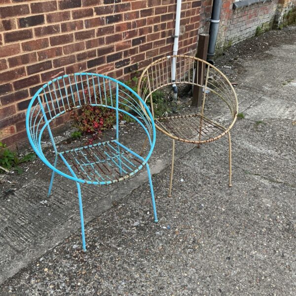 Pair of vintage metal garden chairs awaiting restoration in a garden.