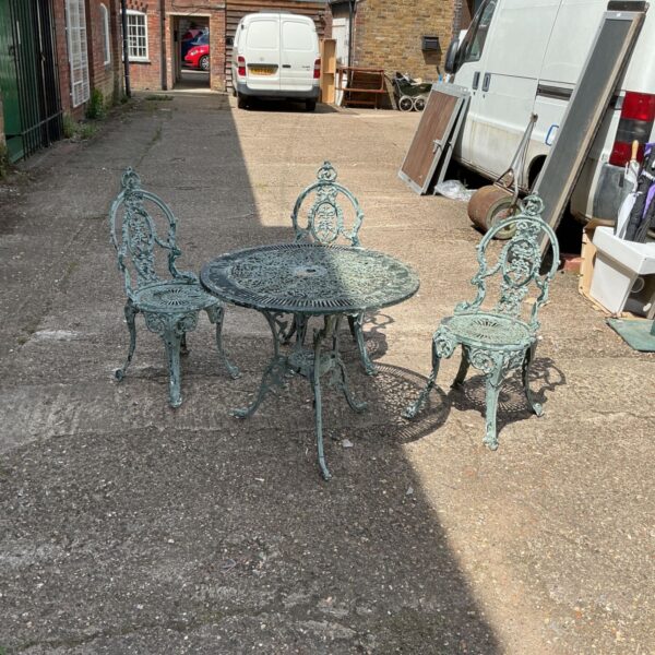 Vintage metal patio set with table and chairs in a garden setting.