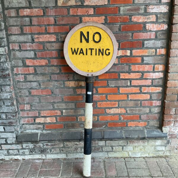 Vintage cast iron no waiting sign on striped pole.