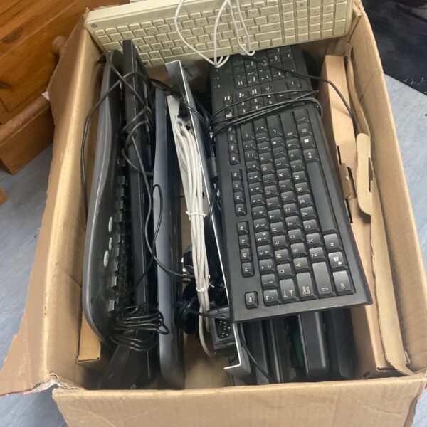 Assorted vintage PC keyboards and mice in a cardboard box.
