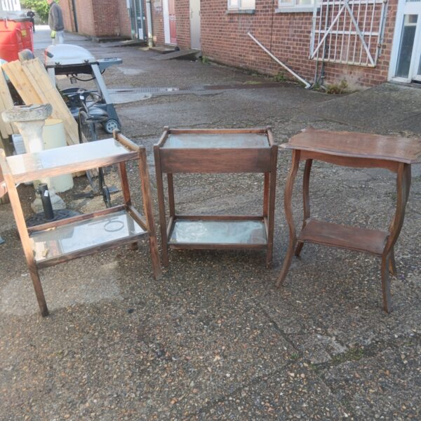 Lot of three vintage wooden side tables in a garden setting.