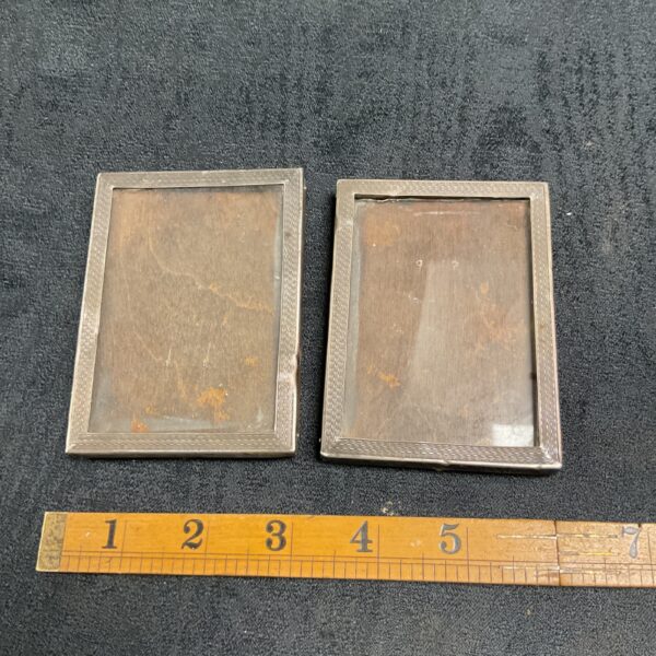 Pair of vintage hallmarked silver photograph frames on dark background.