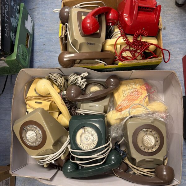 Lot of vintage telephones in various colours and styles.
