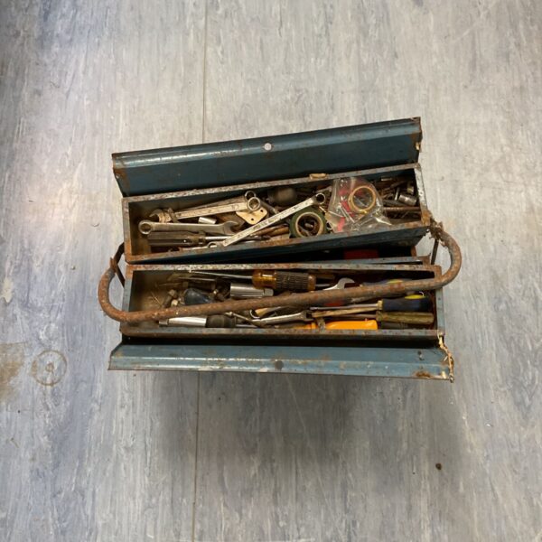 Vintage metal toolbox filled with assorted hand tools.