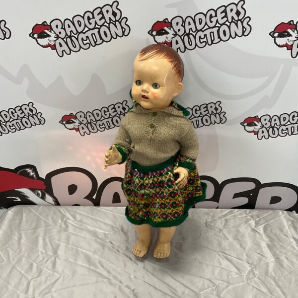 Vintage walking doll with knitted sweater and patterned skirt.