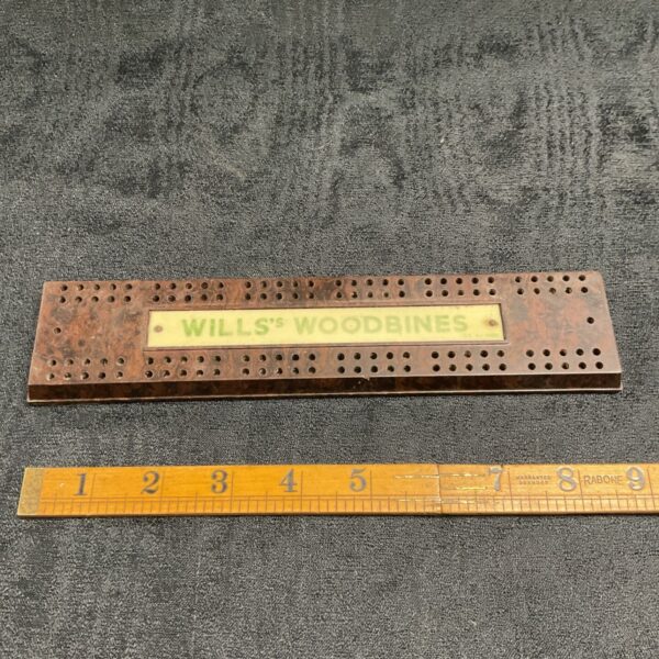 Vintage Wills Woodbines cribbage board with peg holes.