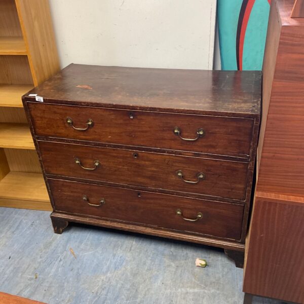 Vintage wood chest of drawers with brass handles for bedroom storage.