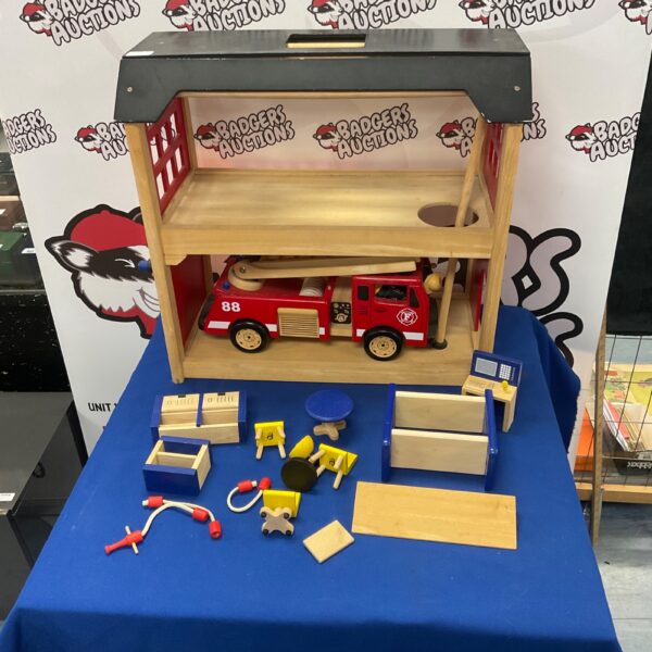 Vintage wooden fire station with red fire engine and accessories.
