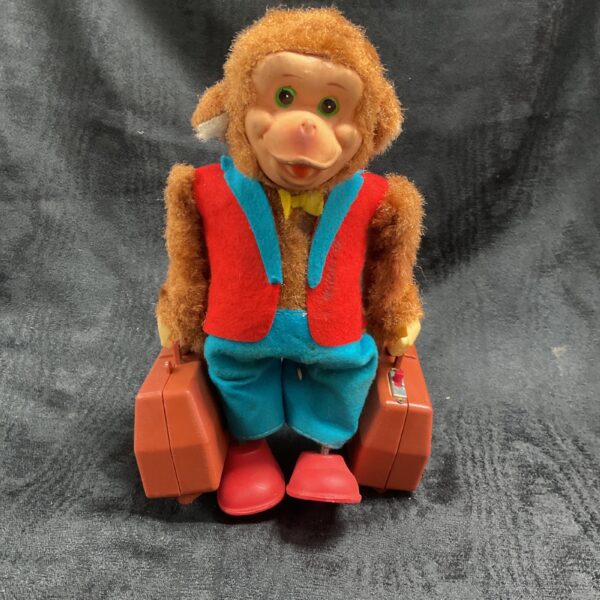 Front view of vintage Yano Man monkey toy with suitcases.