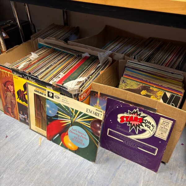 Large lot of vintage 12 inch vinyl records stacked on a floor.
