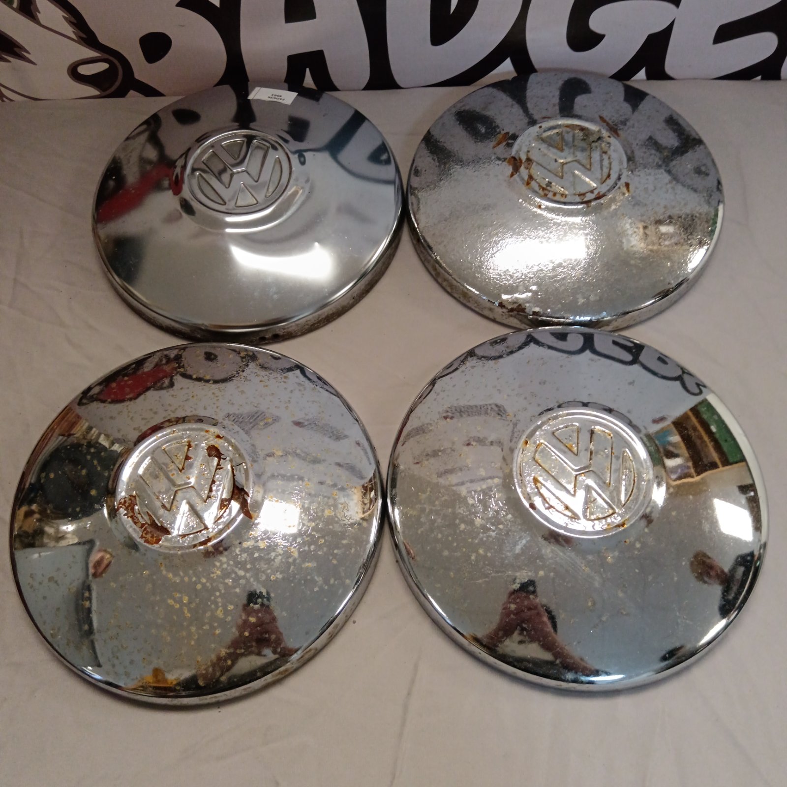 Chrome VW hub caps with Volkswagen logo, vintage car parts.