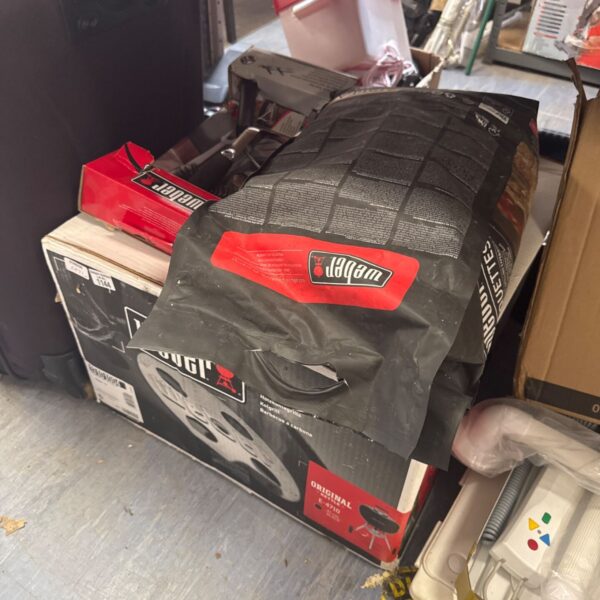 Weber kettle barbecue with charcoal and utensil set for outdoor cooking.