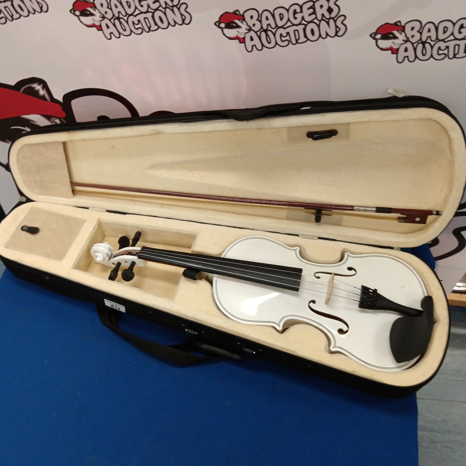 White violin in open case with bow, a unique musical instrument.