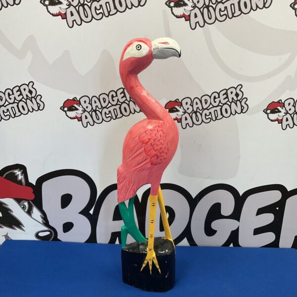 Vibrant pink wooden flamingo sculpture, a charming garden ornament.