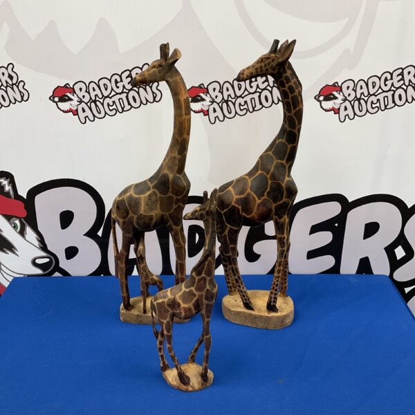Three carved wooden giraffe figures on display.