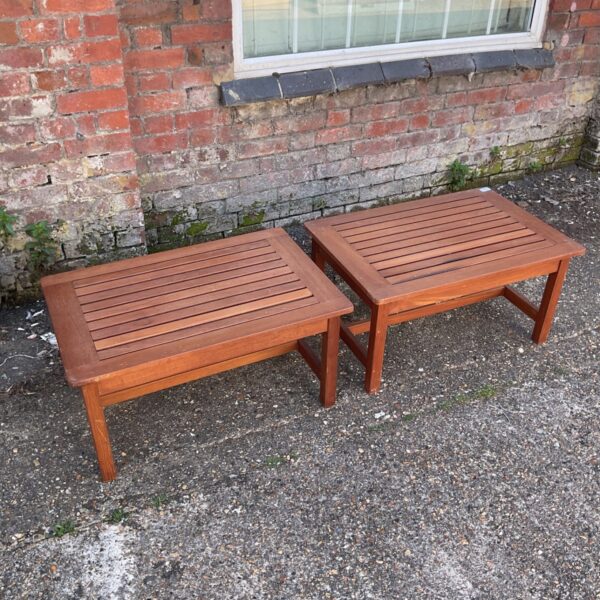 Two wooden slatted tables in a garden setting.