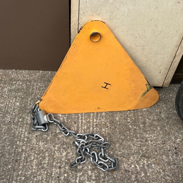 Yellow metal wheel clamp with chain for vehicle security.