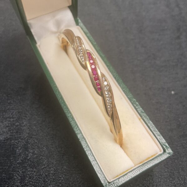 18ct gold bangle with rubies and diamonds displayed in a presentation box.