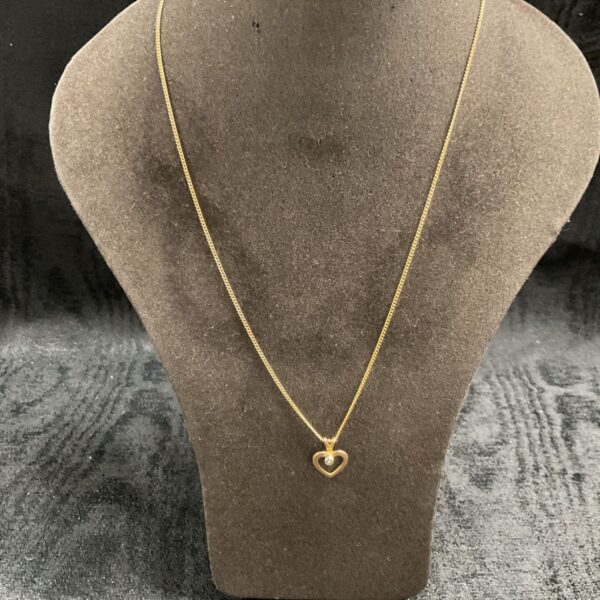 9ct gold necklace with a heart pendant on a neutral background.