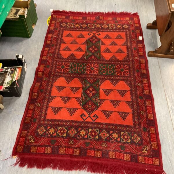 Vibrant red Afghan rug with geometric patterns and a textured wool pile.