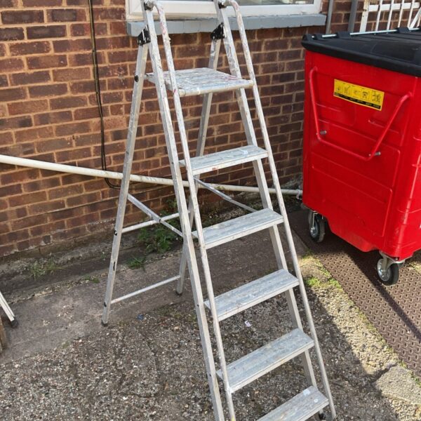 Aluminium platform step ladder leaning against a brick wall.