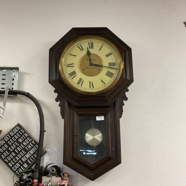 Antique Ansonia New York School wall clock with a dark wooden case.