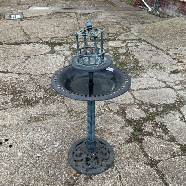 Antique cast iron bird bath in a garden setting.