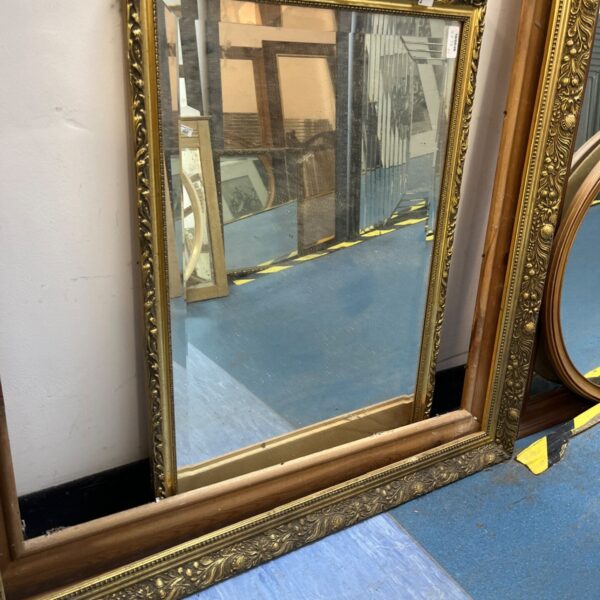 Antique gold framed mirror with ornate detailing.