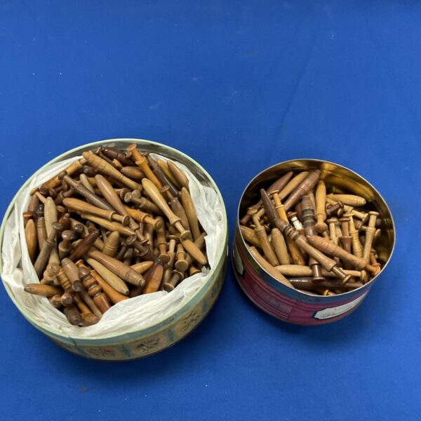 Antique lace bobbins in a decorative tin, a large collection.