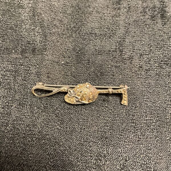 Antique markasite brooch featuring a riding crop and top hat design.