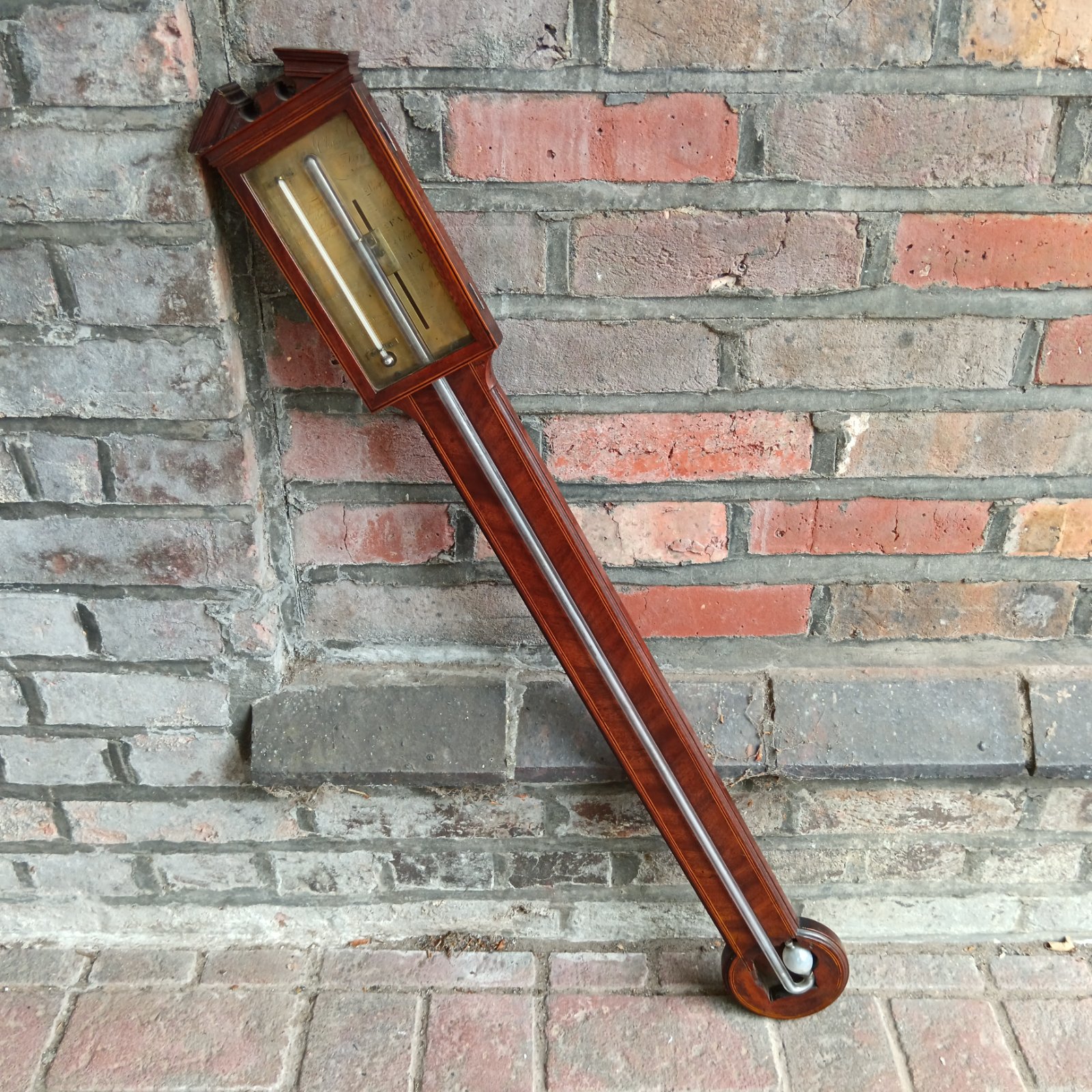 Antique mercury stick barometer with brass fittings and visible mercury.
