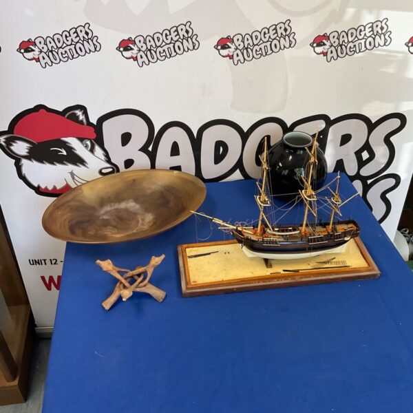 Antique model ship with hand carved bowl on display.