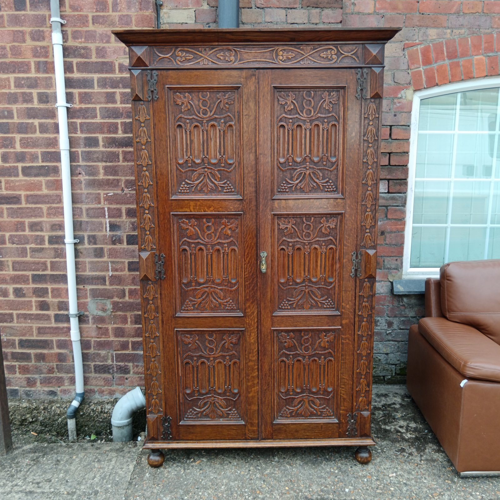 Intricately carved antique oak wardrobe with detailed floral panels.