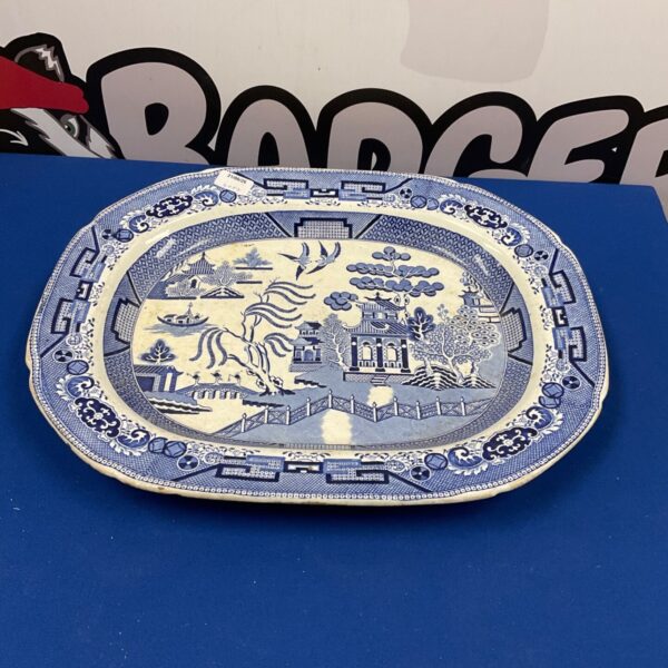 Antique willow pattern platter with blue and white design.