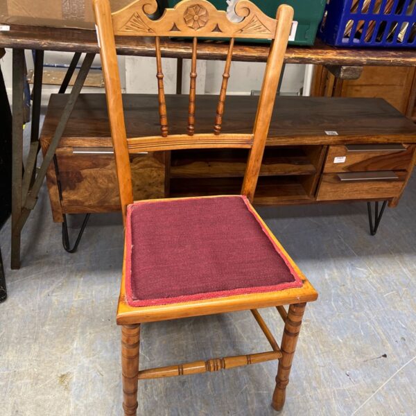 Antique wooden chair with carved backrest and red upholstered seat.