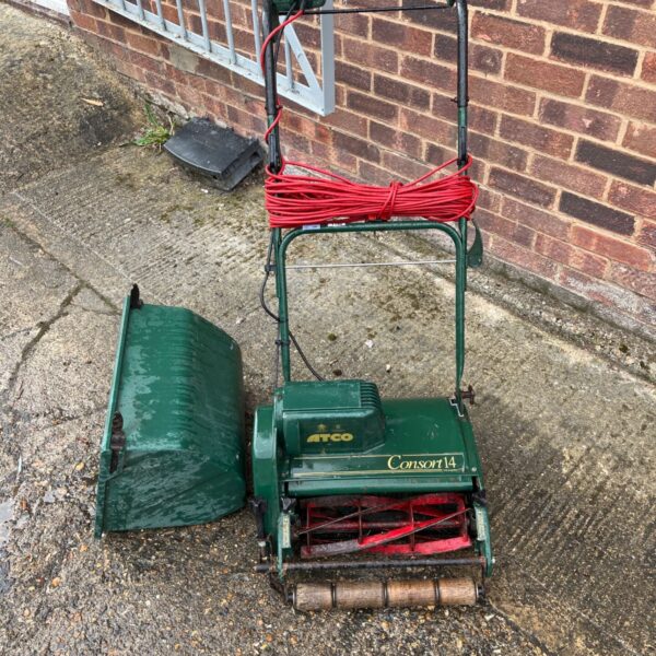 Green Atco Consort 14 electric cylinder mower in a garden setting.