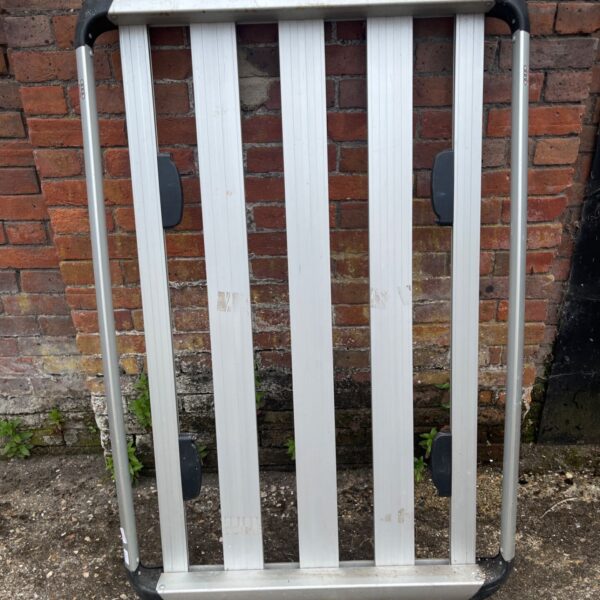 Audi roof rack basket with black joints, shown against a brick wall.