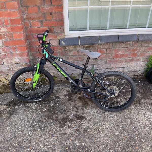 Black and orange B twin children’s bike with front suspension.