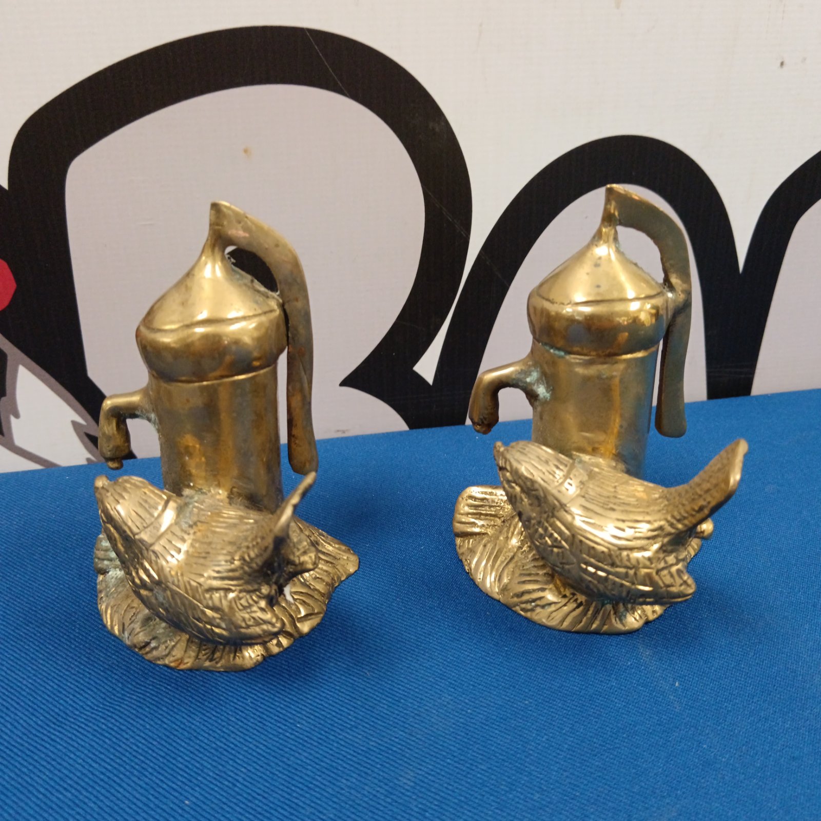 Vintage brass bird and water pump ornaments on display.