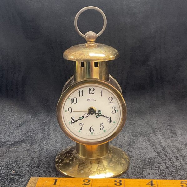 Vintage brass lantern alarm clock with a white face.