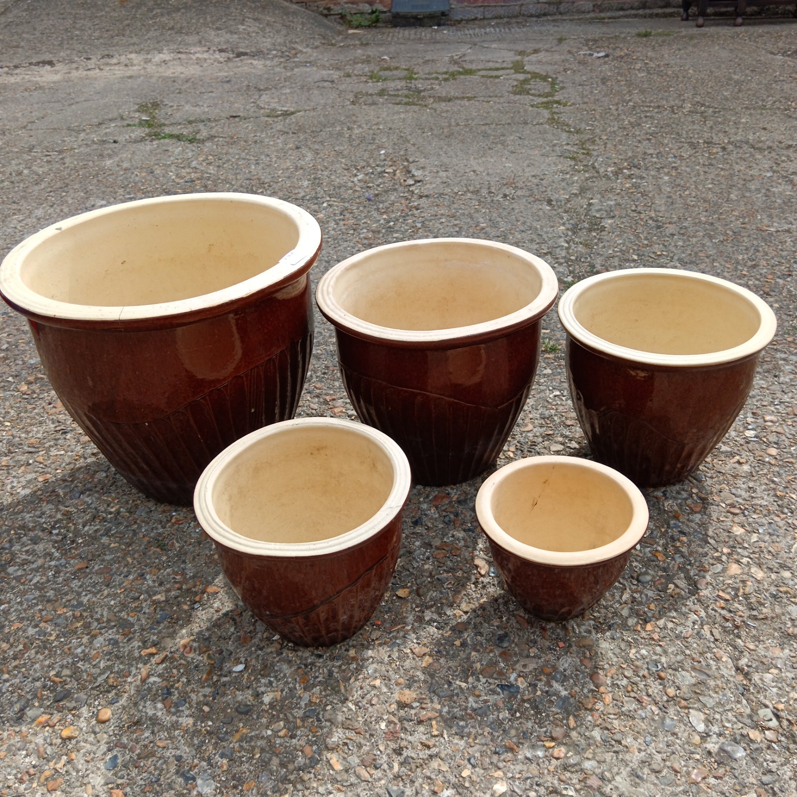 Set of five brown glazed terracotta plant pots for garden or home.