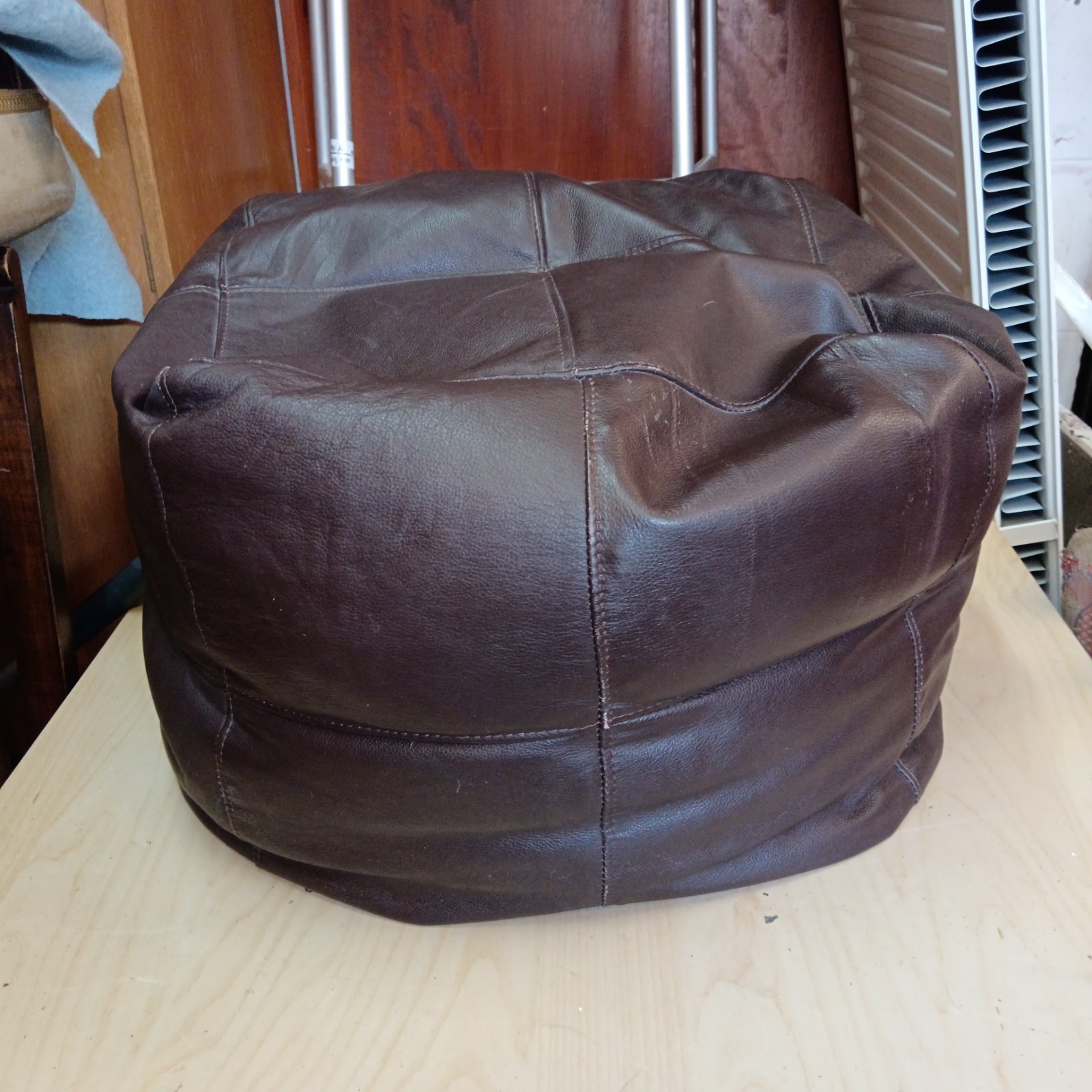 Small brown leather bean bag chair for relaxed seating.