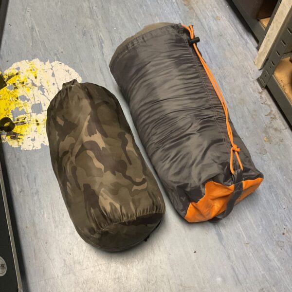 Two camouflage sleeping bags rolled up, ready for outdoor adventures.