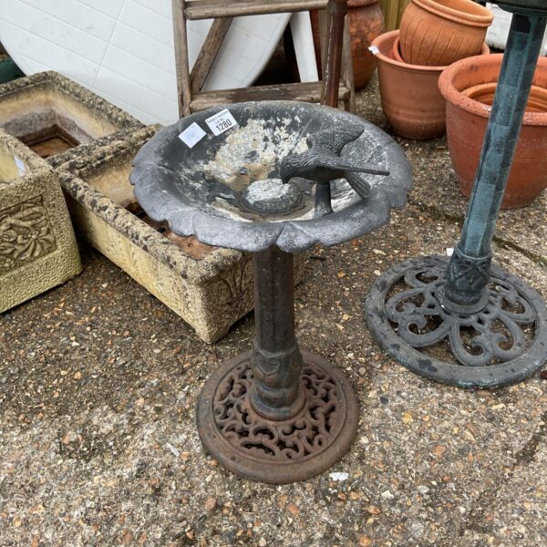 Vintage cast iron bird bath in a garden setting.
